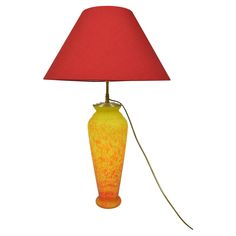 a yellow lamp with a red shade on the base and a cord attached to it