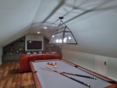 a pool table in the middle of a room with an entertainment center and couches