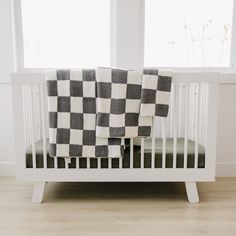 a white crib with a black and white checkered blanket