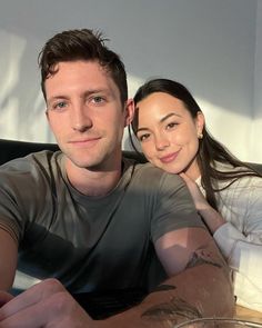 a man sitting next to a woman on top of a bed