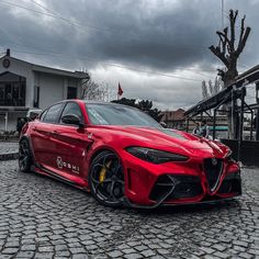 a red sports car is parked on the cobblestone street in front of a building