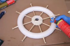 a person in blue gloves is painting a steering wheel with white paint and glues