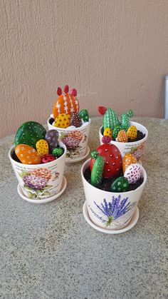 three small ceramic pots filled with different colored cacti on top of a table