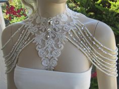 a mannequin wearing a white dress with pearls and beads on the neckline