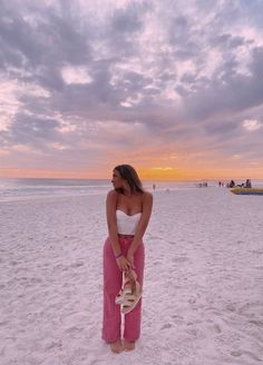 a woman in pink pants standing on the beach