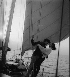 a man and woman kissing on the deck of a sailboat