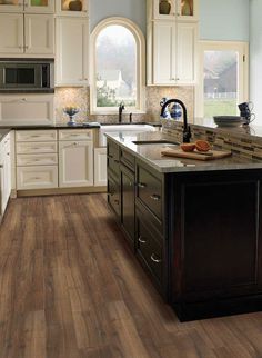 a large kitchen with white cabinets and wood flooring on the countertops, along with an island