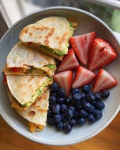 a bowl filled with fruit and quesadillas on top of a table