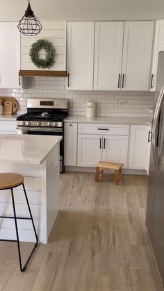 a kitchen with white cabinets and wood floors