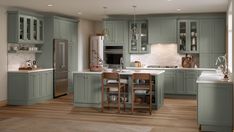 a large kitchen with green cabinets and wooden flooring, along with a dining table