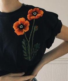 a woman wearing a black shirt with orange flowers on it