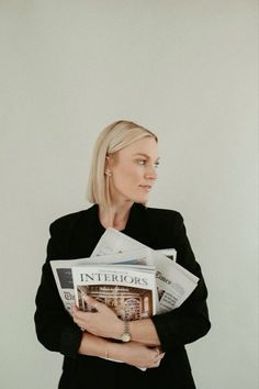 a woman in a black jacket is holding newspapers