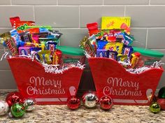 two red baskets filled with candy and christmas candies on top of a countertop