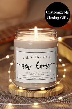 the scent of a new home candle on a wooden table with lights around it and a black circle that says, customize closing gifts