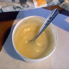 a bowl of soup with a spoon in it sitting on a table next to a newspaper