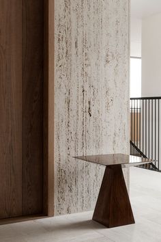 a wooden table sitting on top of a white tiled floor next to a stair case