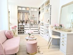 a pink couch sitting in front of a white closet filled with lots of clothes and accessories