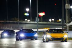 three sports cars driving on a track at night