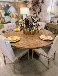 a wooden table with white chairs and yellow plates on it in a room filled with furniture