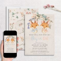 a person holding up a phone next to a baby shower card and its envelope with flowers on it