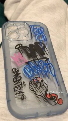 an iphone case with graffiti on it sitting on top of a white sheet covered bed