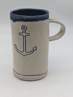 a white and blue coffee mug with an anchor on it