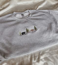 "Embroidered Bear and Moose Sweatshirt -Embroidered on a cotton/polyester blend crewneck sweatshirt, this design is simple and minimalistic, perfect for every outfit! -Embroidery design measures 1.25\" x 5\". -See product pictures for shirt sizing chart. **SWEATSHIRTS ARE IN UNISEX SIZING AND RUN TRUE TO SIZE. -All sweatshirts are handmade on an embroidery machine so there may be slight differences, but we only sell the sweatshirts that meet our high-quality standards. -To maintain the quality o Grey Sweatshirt Embroidery, Cute Sweatshirt Embroidery Ideas, Cute Embroidered Shirts, Machine Embroidered Clothes, Crew Neck Embroidery Ideas, Cute Embroidery Ideas Shirts, Machine Embroidery Tshirt, Embroidery Designs For Shirts, Embroidery Designs Sweatshirt