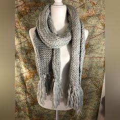 a white mannequin wearing a gray knitted scarf on top of a map