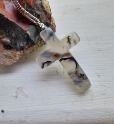 a glass cross sitting on top of a wooden table next to a piece of rock