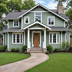 a green house with white trim and two story windows on the second floor, along with a walkway leading up to the front door