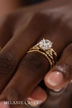 a close up of a person's hand with two rings on their fingers and the other hand holding an engagement ring