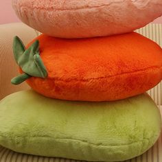 three pillows stacked on top of each other in the shape of carrots and broccoli