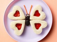 a white plate topped with heart shaped pastries on top of a pink tablecloth