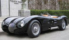 an old black sports car parked in front of a building