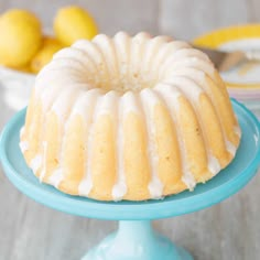 a bundt cake with white icing on a blue plate next to lemons