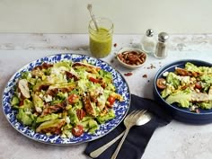 two plates filled with salad next to a glass of green juice