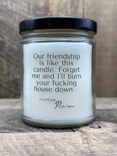 a candle with a quote on it sitting on a wooden table