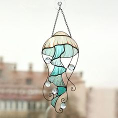 a stained glass wind chime hanging from a chain in front of a cityscape