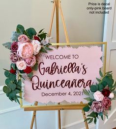 a welcome sign with flowers and greenery hanging from it's frame in front of a door