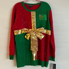 a green and red sweater with gold foil on the side, tied to a hanger