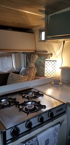 a stove top oven sitting inside of a kitchen next to a microwave under a window