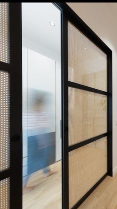 a person walking through an open door in a room with wooden floors and walls,