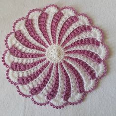 a crocheted doily with pink and white stripes on the center is shown