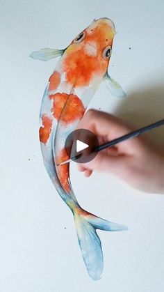 someone is painting a koi fish with watercolors