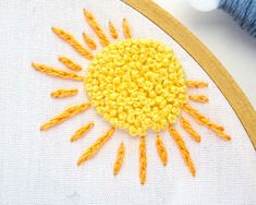 the sun is made out of yellow thread on a white canvas with a wooden frame