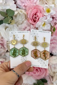 These Cheers Flowers & Brass Earrings combine modern minimalism with natural elements, making them a statement accessory you'll love. Crafted with non-toxic resin and real dried botanicals, each pair is unique and perfect for everyday wear. Elevate your style with these stunning earrings. MATERIAL USED: Non-Toxic Epoxy Resin, Brass Frame, Hypoallergenic Hoops, Dried Flowers, botanicals, terrariums. CARE - Don't store in high heat, which can cause shape defects and flowers to fade. Due to the jew Nature-inspired Green Earrings With Pressed Flowers, Nickel-free Botanical Flower Earrings, Nature-inspired Birth Flower Earrings, Dried Botanicals, Modern Minimalism, Natural Elements, Stunning Earrings, Brass Frame, Brass Earrings