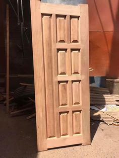 a wooden door sitting in the middle of a floor next to a pile of wood