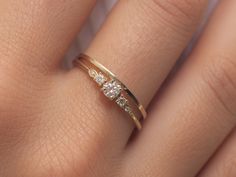 a woman's hand wearing a gold ring with three diamonds on it and the band is