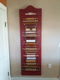 a red wall hanging on the side of a white door next to a wooden shelf filled with books