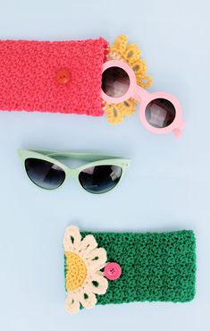 two crocheted hats and sunglasses on a white surface